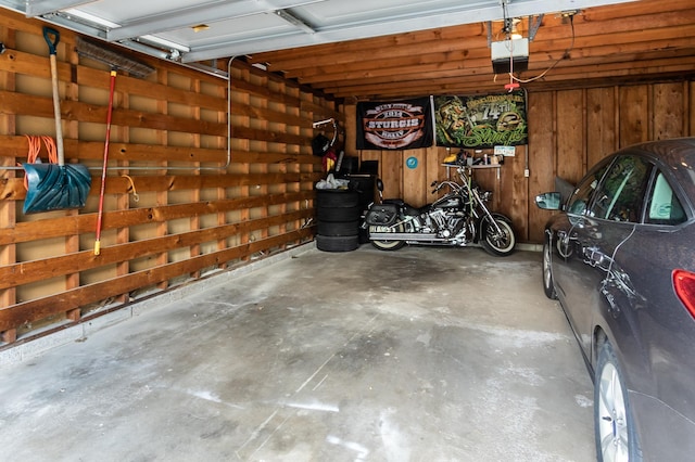 garage with a garage door opener and wooden walls