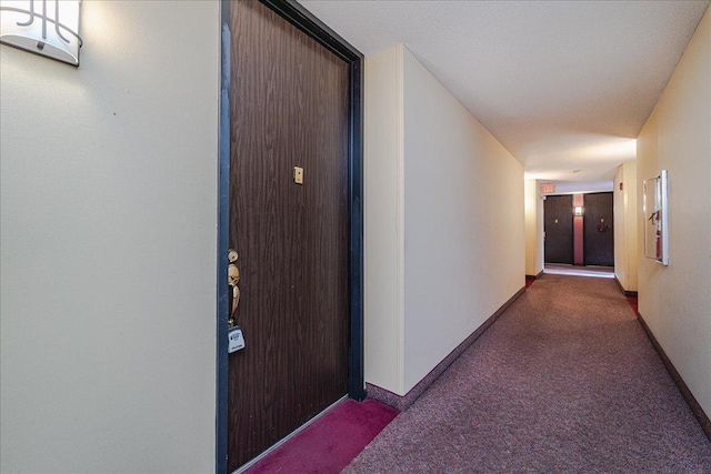 hall with dark colored carpet