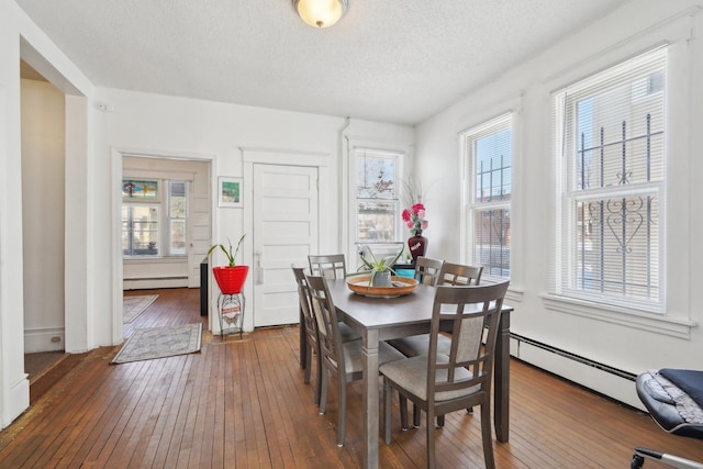 dining area with a textured ceiling, a baseboard heating unit, and dark hardwood / wood-style flooring