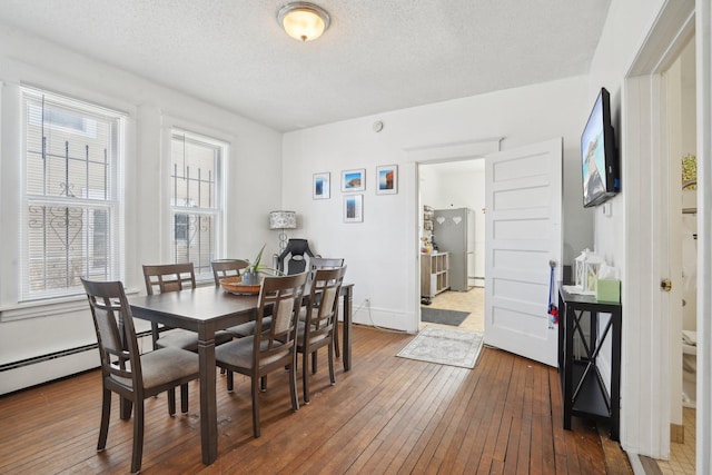 dining space with dark wood-type flooring, a textured ceiling, and plenty of natural light