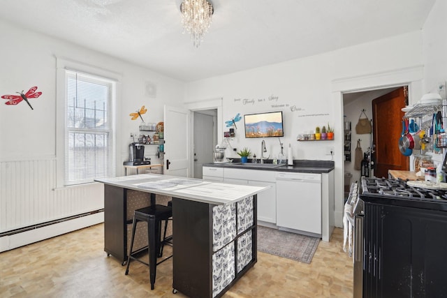 kitchen with white dishwasher, white cabinetry, a kitchen breakfast bar, sink, and stainless steel gas stove