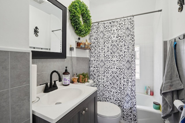 full bathroom with tile walls, toilet, vanity, and shower / bath combo