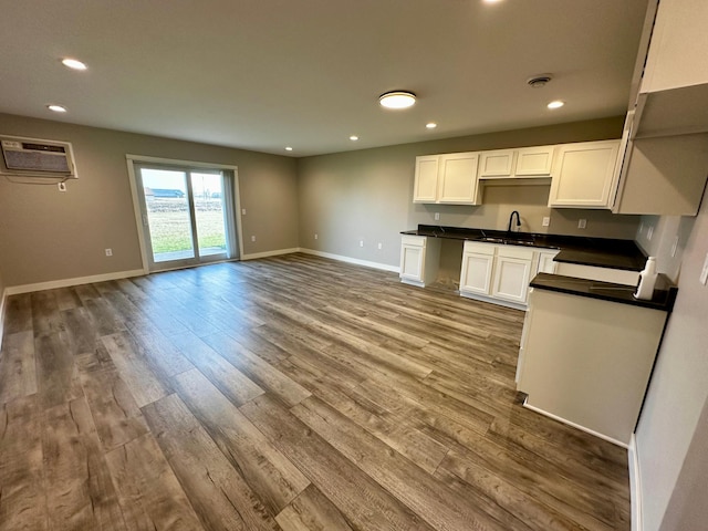 kitchen featuring white cabinetry, sink, light hardwood / wood-style floors, and a wall mounted AC