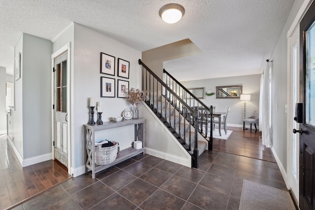 entrance foyer featuring a textured ceiling and dark tile patterned floors