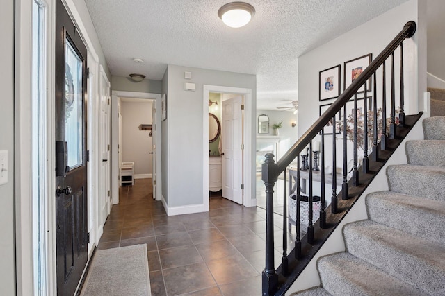 entryway featuring a textured ceiling, ceiling fan, plenty of natural light, and dark tile patterned flooring