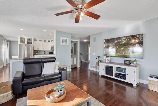 living room with ceiling fan, dark hardwood / wood-style floors, and a textured ceiling