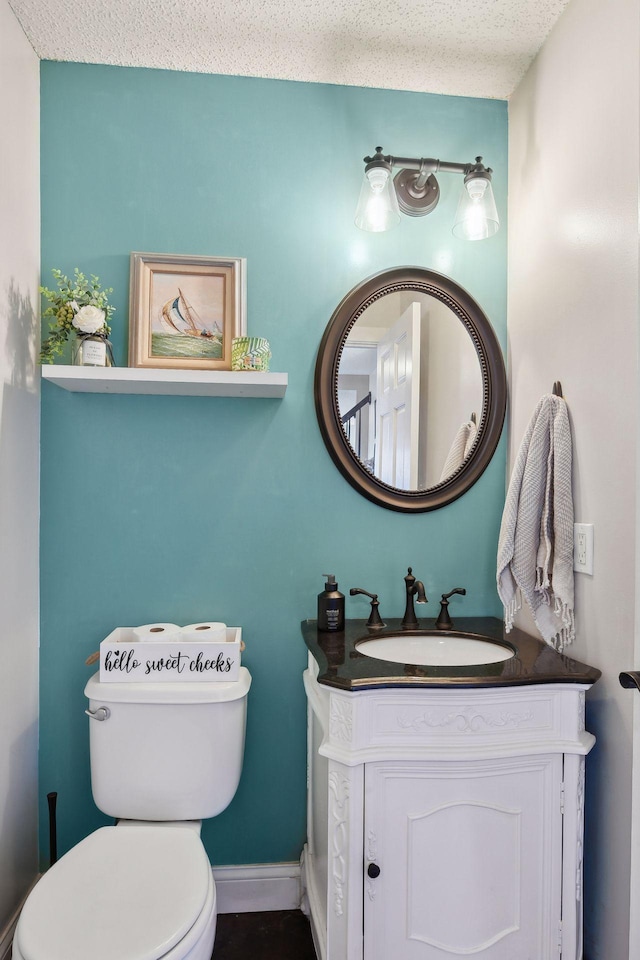 bathroom with a textured ceiling, toilet, and vanity