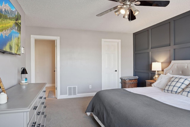 carpeted bedroom featuring ceiling fan and a textured ceiling