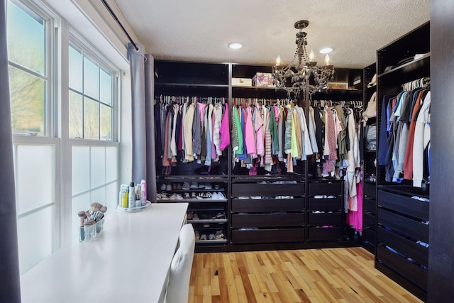 walk in closet with light hardwood / wood-style flooring and a notable chandelier