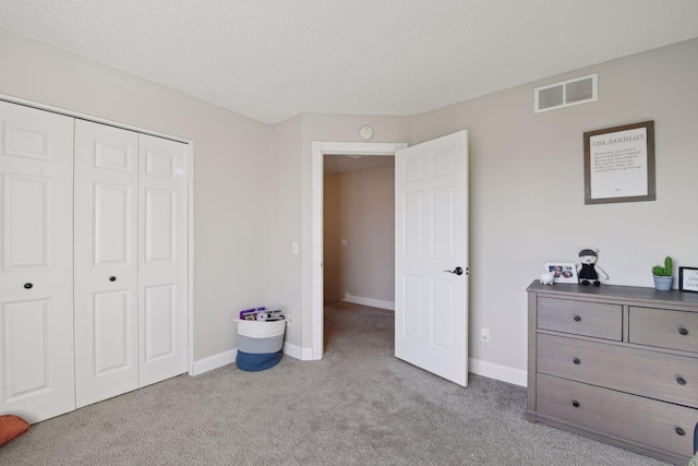 carpeted bedroom with a textured ceiling and a closet