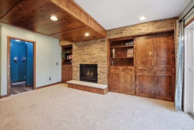 unfurnished living room with wooden ceiling, carpet, built in features, and a stone fireplace