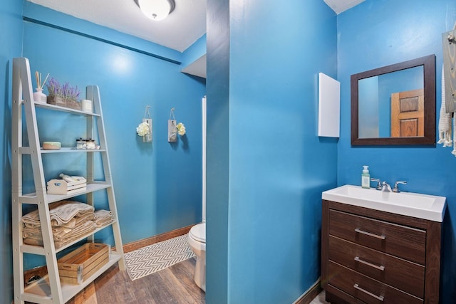 bathroom featuring hardwood / wood-style flooring, toilet, and vanity