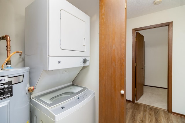 laundry room featuring a textured ceiling, light hardwood / wood-style flooring, stacked washer and clothes dryer, and water heater