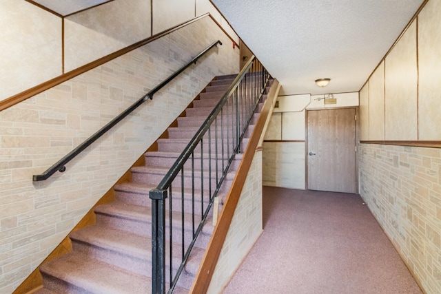 staircase featuring carpet floors and a textured ceiling