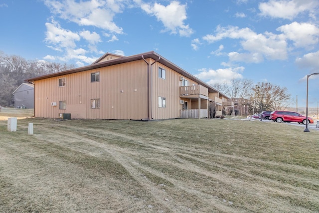 view of home's exterior with a lawn, central AC, and a balcony