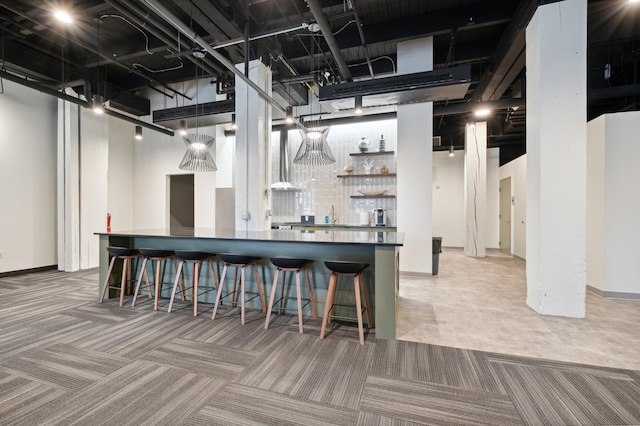 kitchen featuring a kitchen bar, carpet floors, and sink