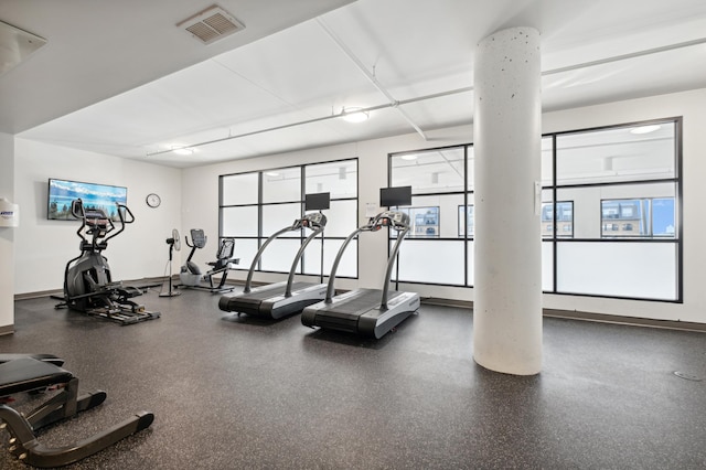 exercise room featuring baseboards, visible vents, and ornate columns