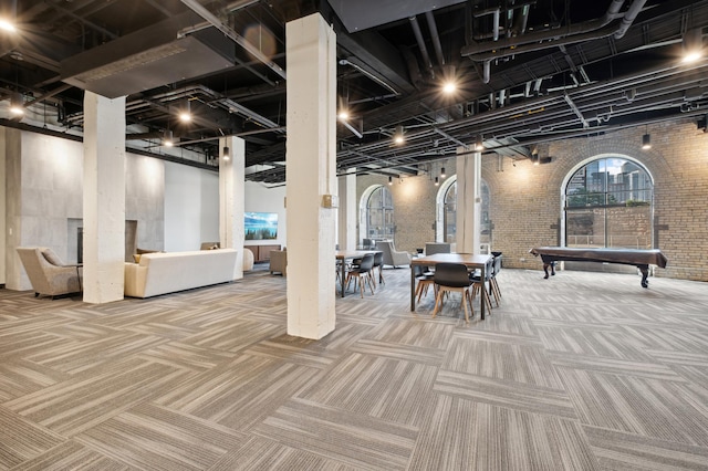 below grade area with brick wall, pool table, and carpet flooring