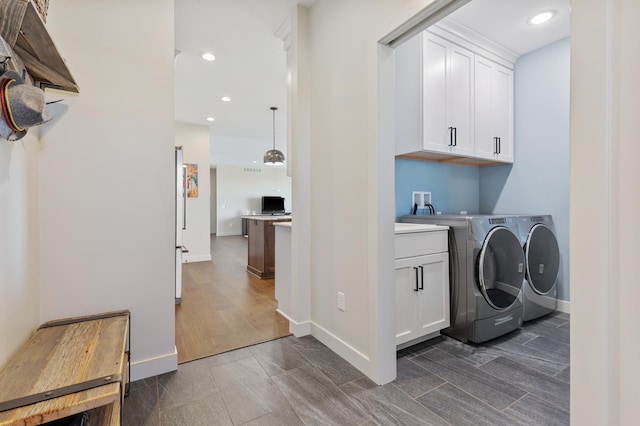 clothes washing area with cabinets and washing machine and dryer