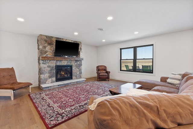 living room featuring hardwood / wood-style flooring and a stone fireplace