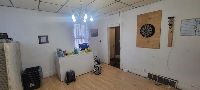 interior space featuring a drop ceiling, wood-type flooring, and a notable chandelier