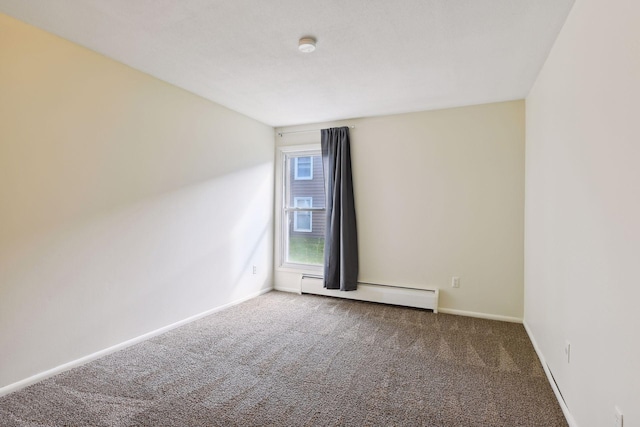 spare room featuring dark colored carpet and a baseboard heating unit