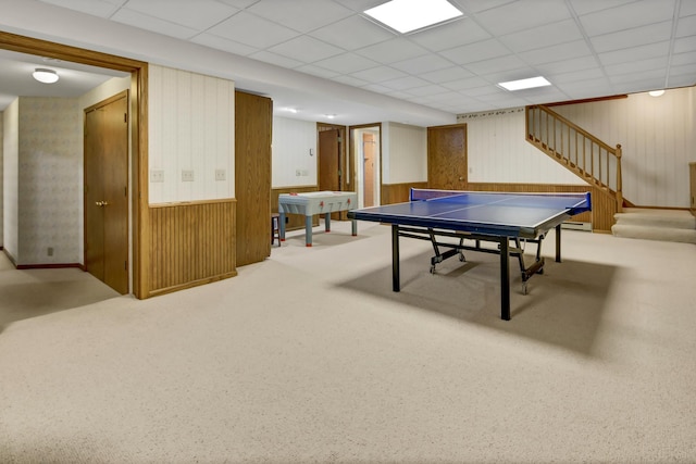 recreation room with wooden walls, light carpet, and a drop ceiling