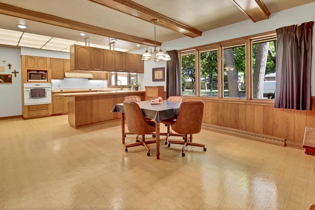 dining space featuring wood walls, sink, beam ceiling, a baseboard heating unit, and an inviting chandelier