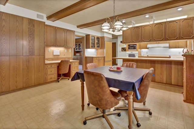 dining area featuring built in desk, wood walls, beamed ceiling, sink, and a notable chandelier