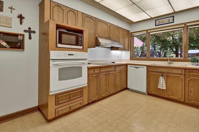 kitchen featuring white appliances, sink, and backsplash