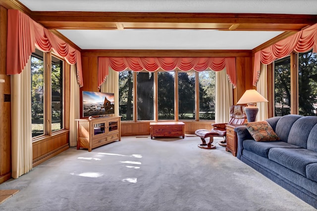 living room featuring beam ceiling, wooden walls, light colored carpet, and a healthy amount of sunlight