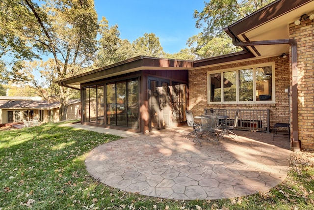 rear view of property featuring a patio, a sunroom, and a lawn