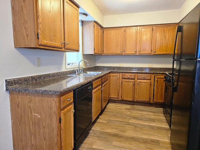 kitchen with black appliances, light hardwood / wood-style floors, and sink