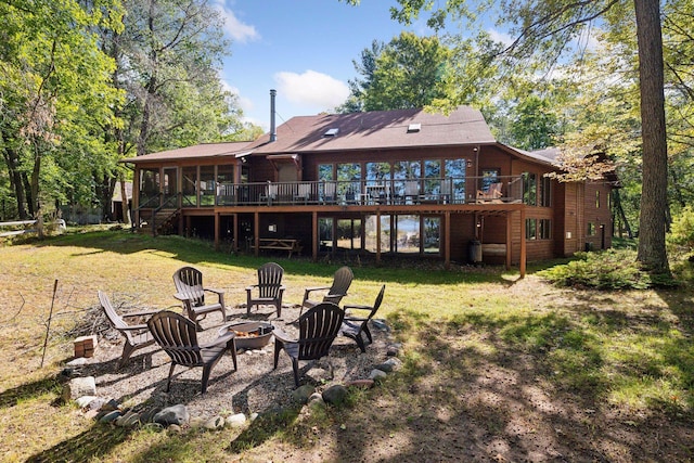 rear view of house with a yard, an outdoor fire pit, and a wooden deck