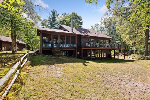 back of property with a yard, a deck, and a sunroom