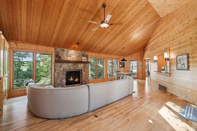 living room featuring ceiling fan, a stone fireplace, high vaulted ceiling, wood ceiling, and light wood-type flooring