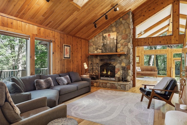 living room featuring a skylight, wooden ceiling, light hardwood / wood-style flooring, track lighting, and a fireplace