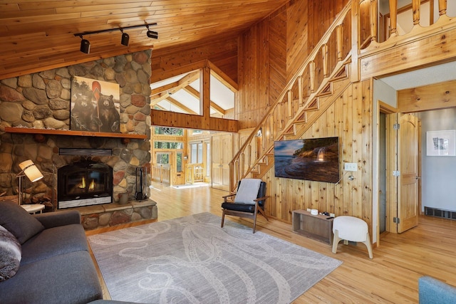 living room with wood walls, rail lighting, hardwood / wood-style flooring, a fireplace, and wood ceiling