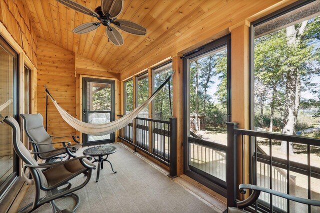 sunroom featuring lofted ceiling, ceiling fan, wooden ceiling, and a healthy amount of sunlight