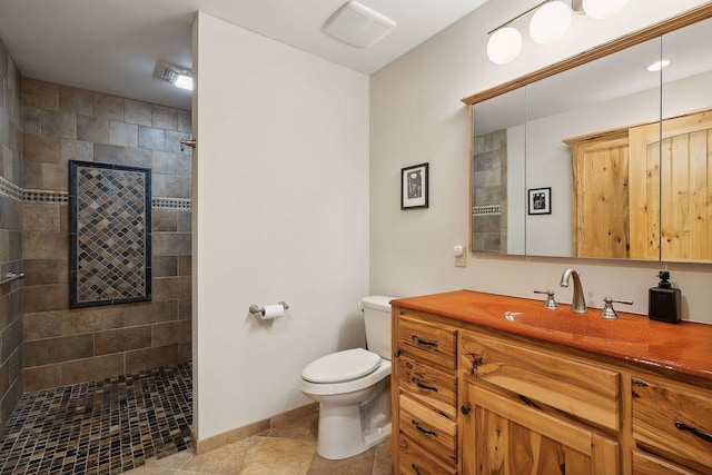 bathroom with tiled shower, vanity, toilet, and tile patterned flooring