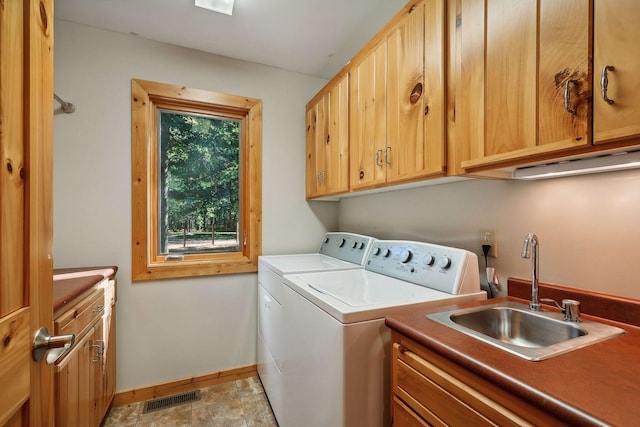 clothes washing area with separate washer and dryer, sink, and cabinets