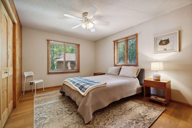 bedroom with ceiling fan, light hardwood / wood-style floors, multiple windows, and a closet