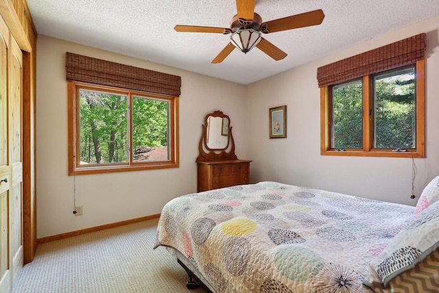 carpeted bedroom with ceiling fan, a textured ceiling, and a closet