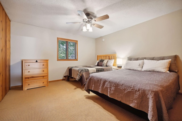 bedroom with ceiling fan, light colored carpet, and a textured ceiling