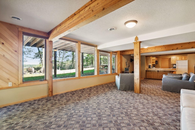 interior space featuring beam ceiling, wooden walls, dark carpet, and a textured ceiling