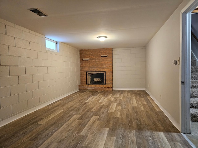 unfurnished living room with dark hardwood / wood-style flooring and a brick fireplace