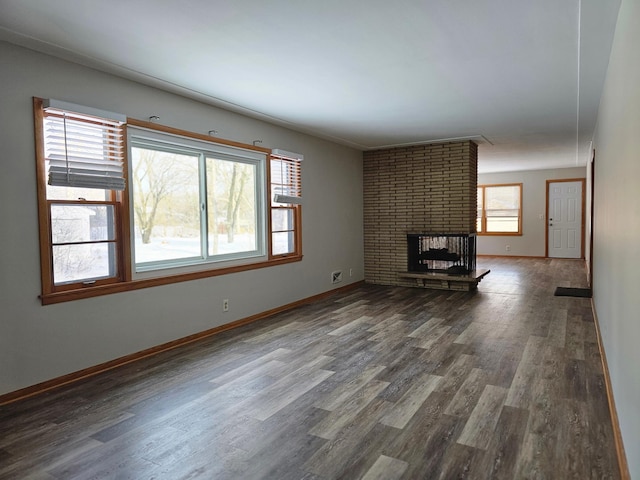 unfurnished living room featuring a fireplace, plenty of natural light, and dark hardwood / wood-style flooring