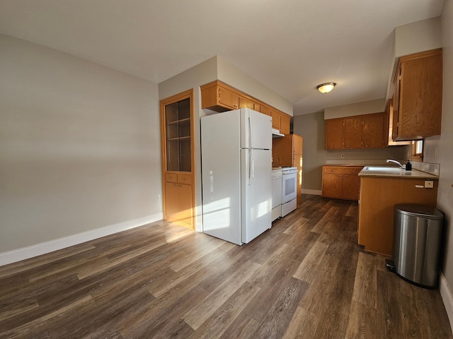 kitchen featuring dark hardwood / wood-style flooring, white appliances, and sink