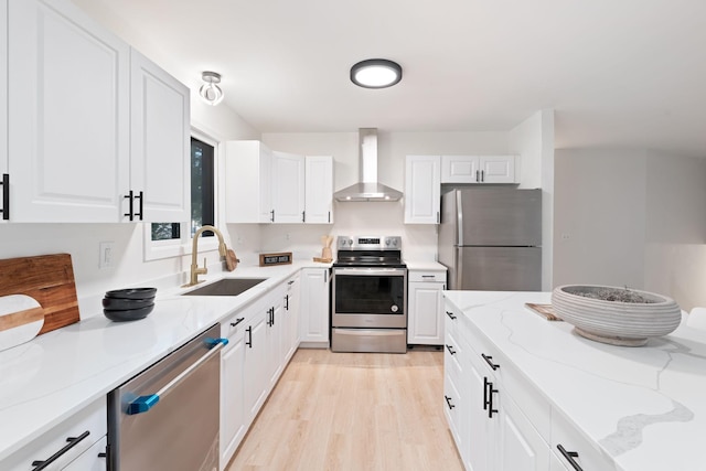 kitchen with white cabinets, sink, wall chimney exhaust hood, appliances with stainless steel finishes, and light stone counters