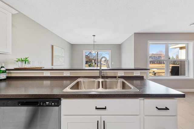 kitchen featuring stainless steel dishwasher, a wealth of natural light, a textured ceiling, sink, and white cabinetry